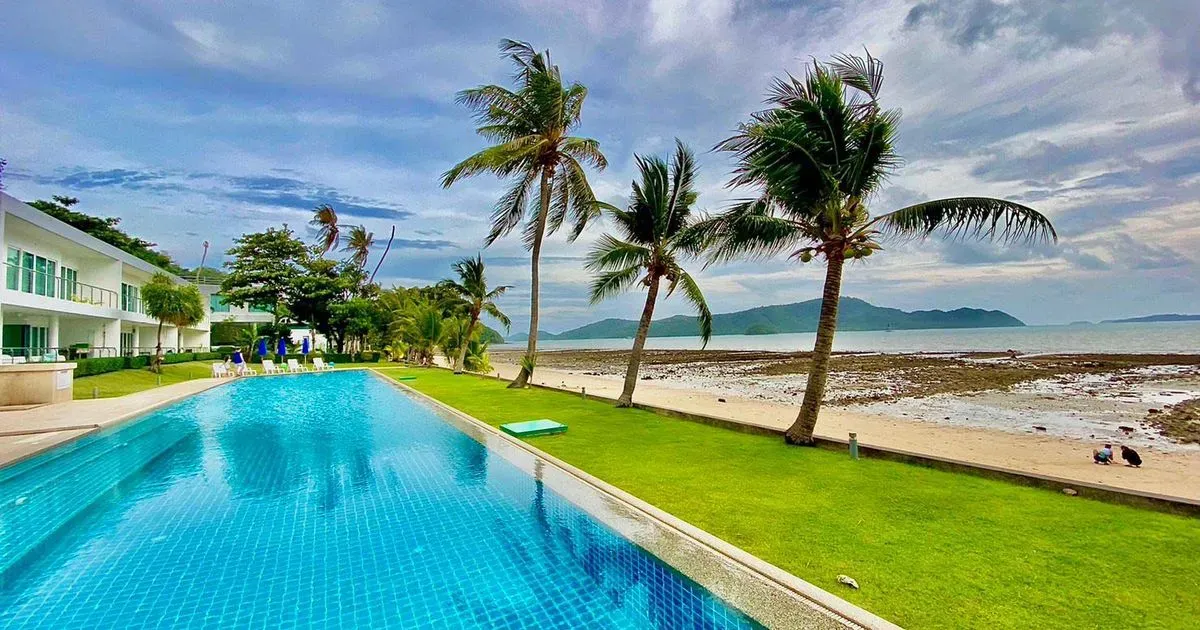 Salt-water pool surrounded by palm trees, manicured lawns, and the beach.